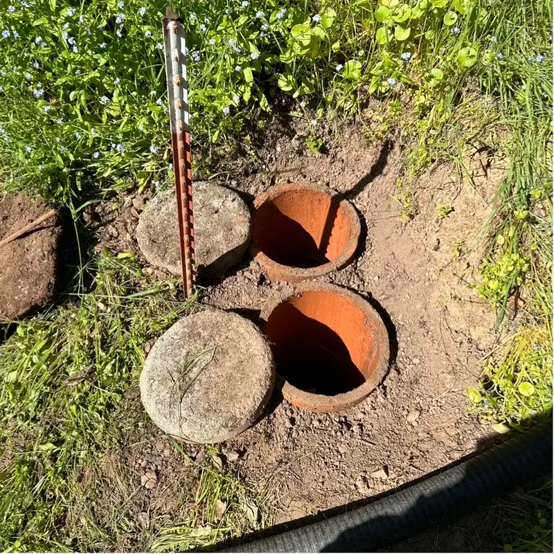 Two septic riser lids uncovered in a yard during an inspection, with a probe rod beside them