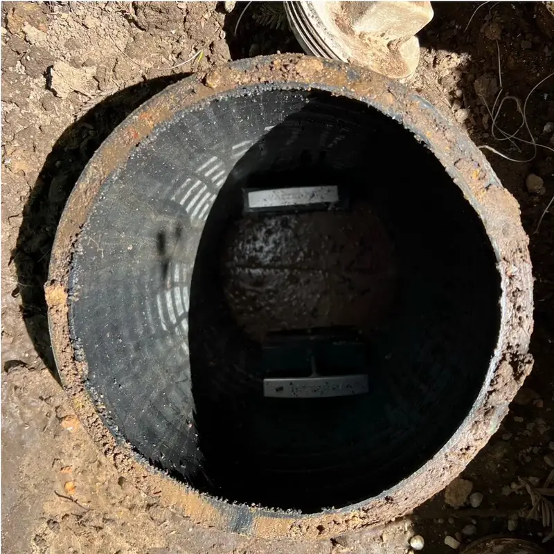 Looking down into an open septic riser at the tank below