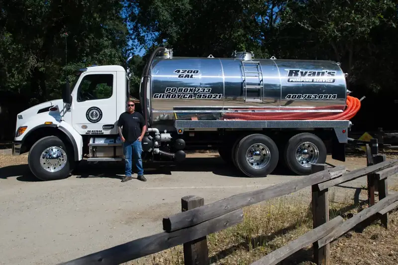 Ryan standing beside his polished 4,200-gallon stainless vacuum truck
